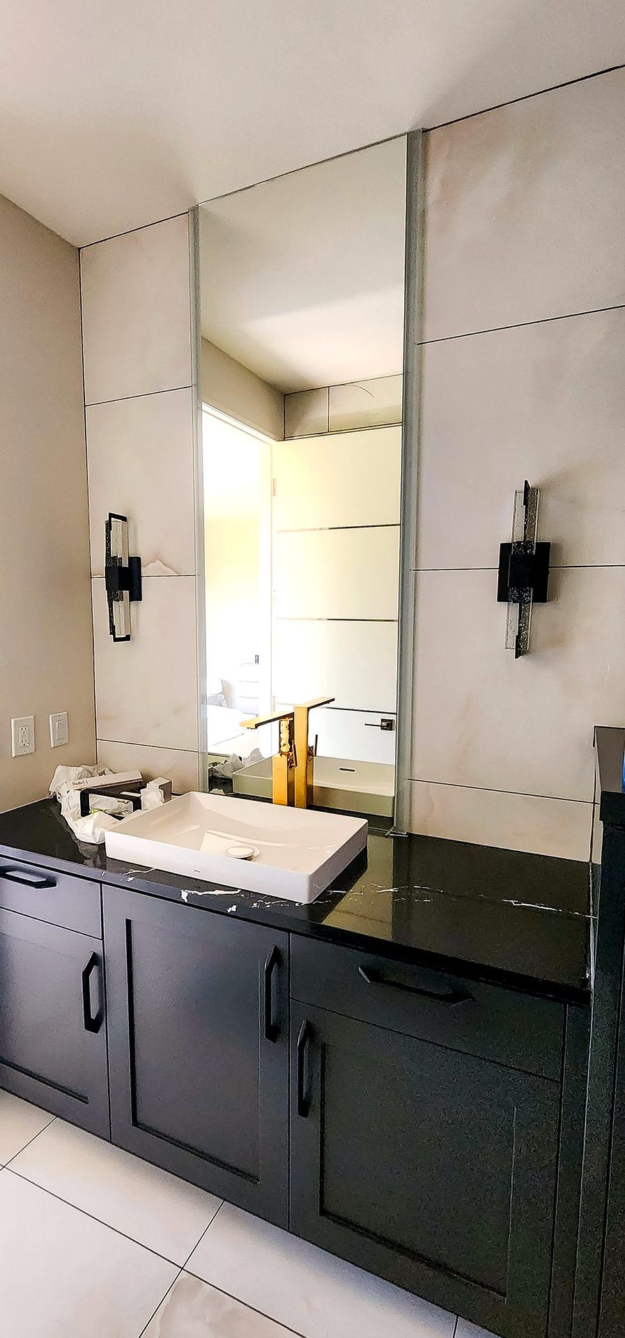 Primary bath with dark cabinetry, black stone counter, vessel sink, and pale wall tile