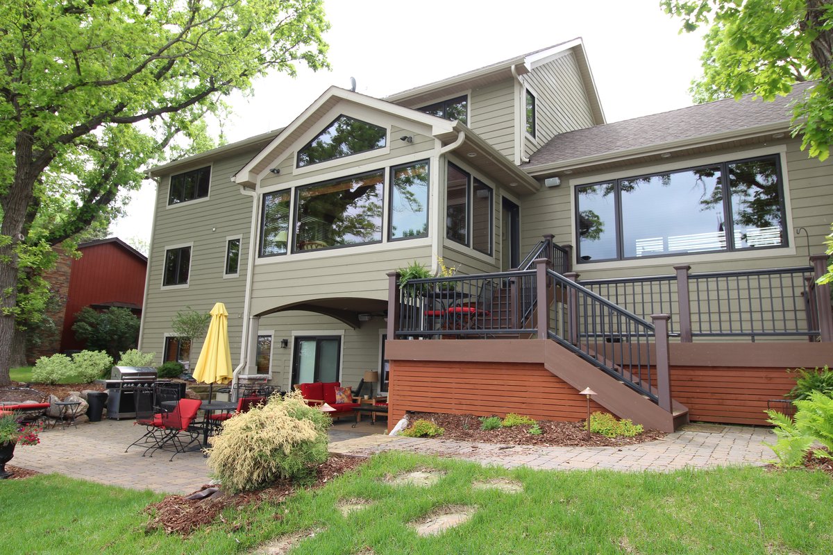 Rear exterior of a lake home with gabled windows, a raised deck and a lower patio.