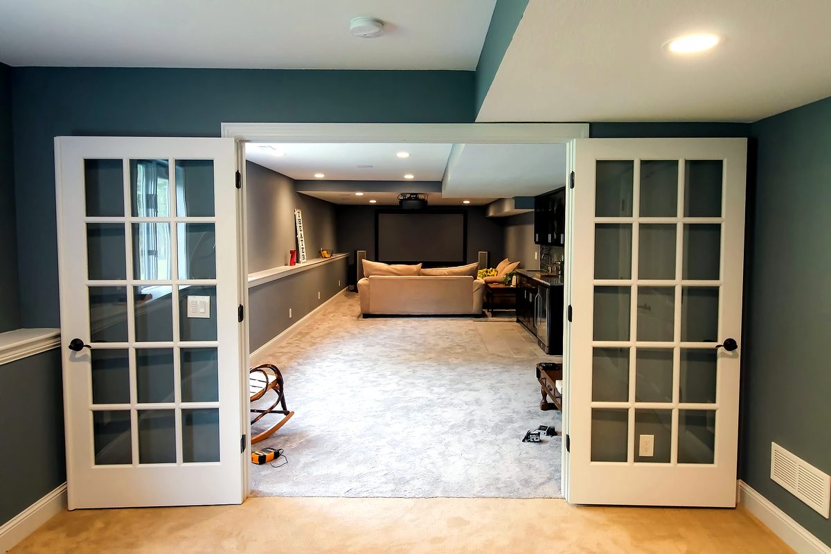 View through french doors into a basement theater area with projection screen