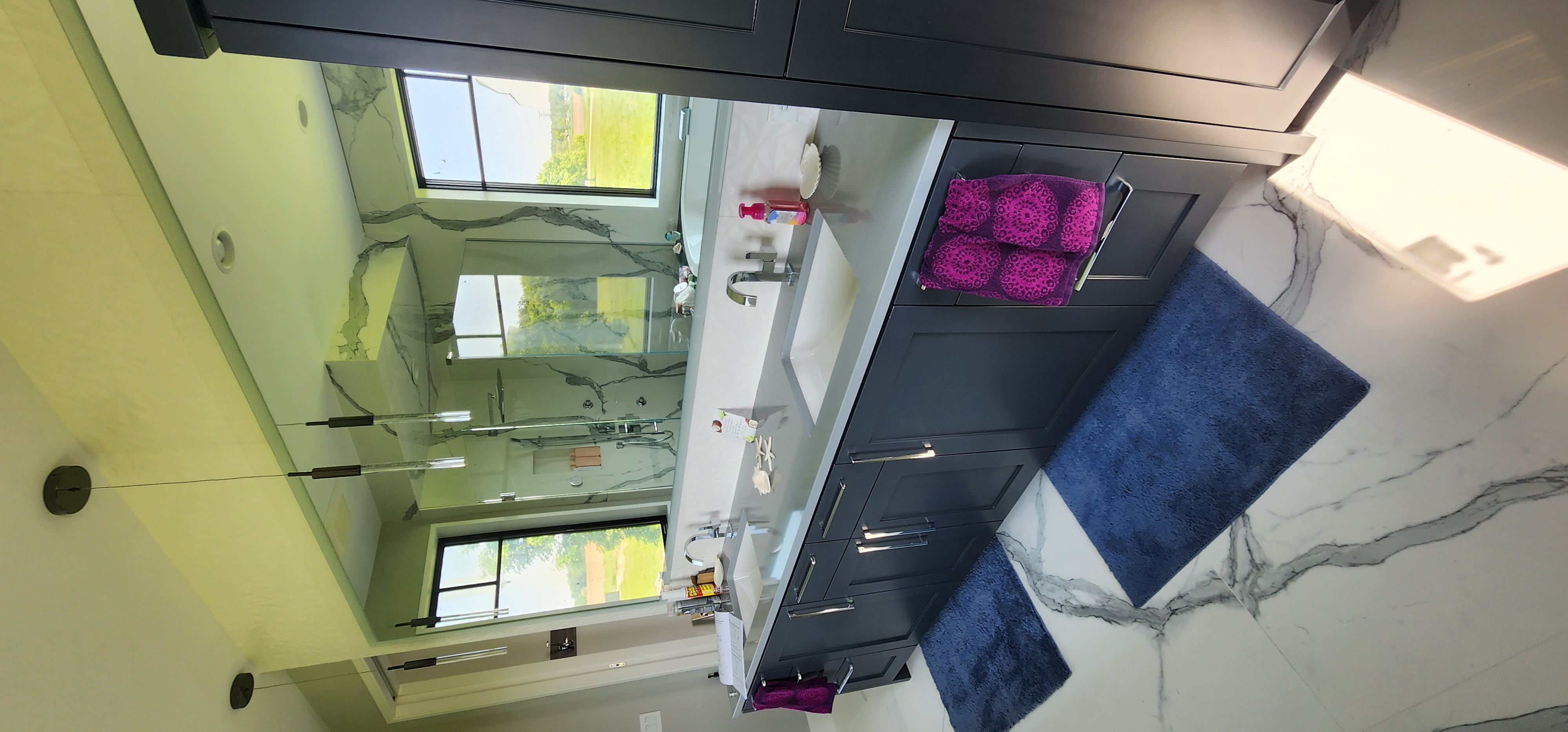 Primary bath double vanity with dark cabinetry, modern hardware, integrated sinks, and large mirror reflecting the shower.