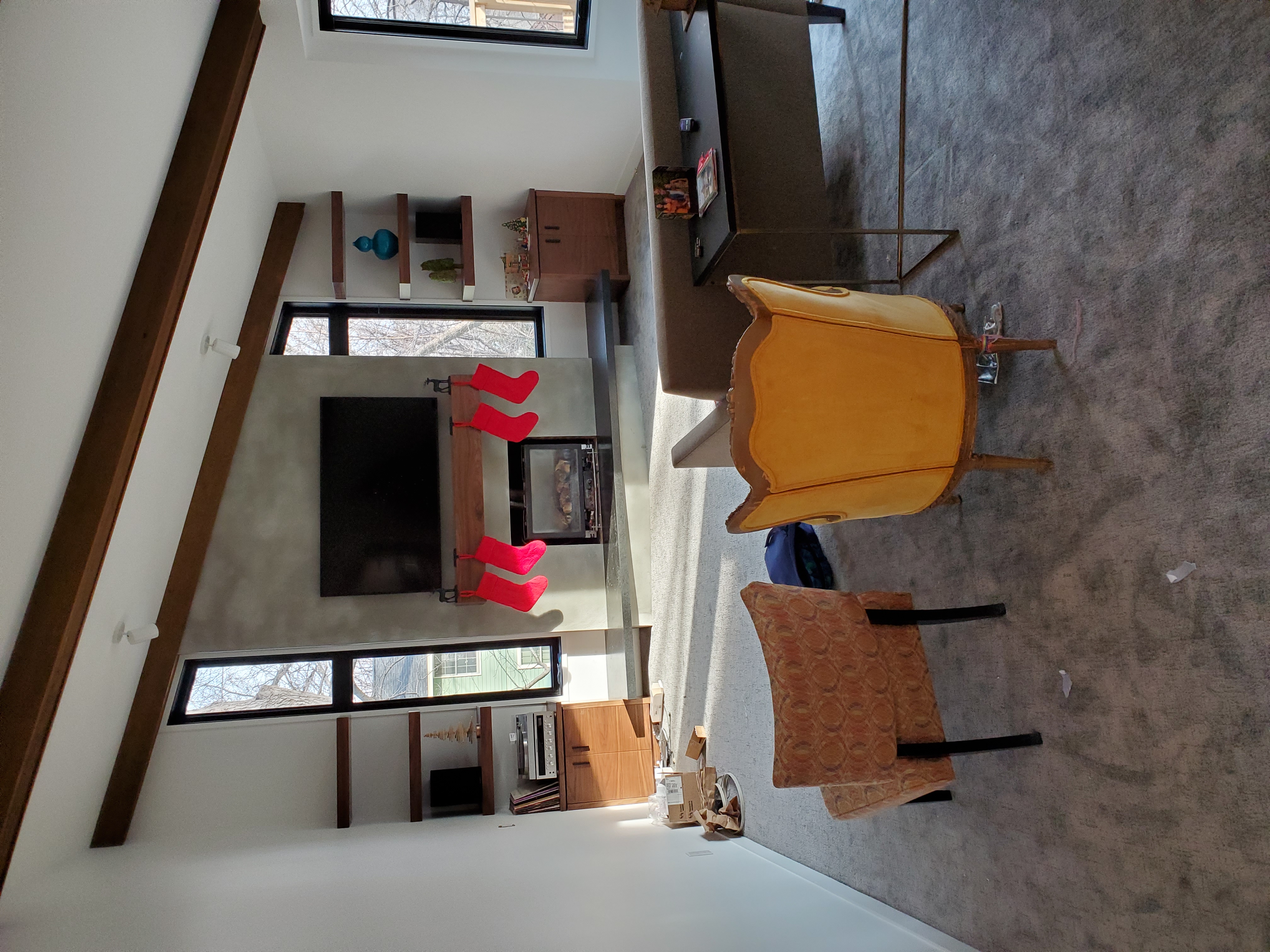 Modern living room with fireplace, wall-mounted TV, and warm wood ceiling beams.