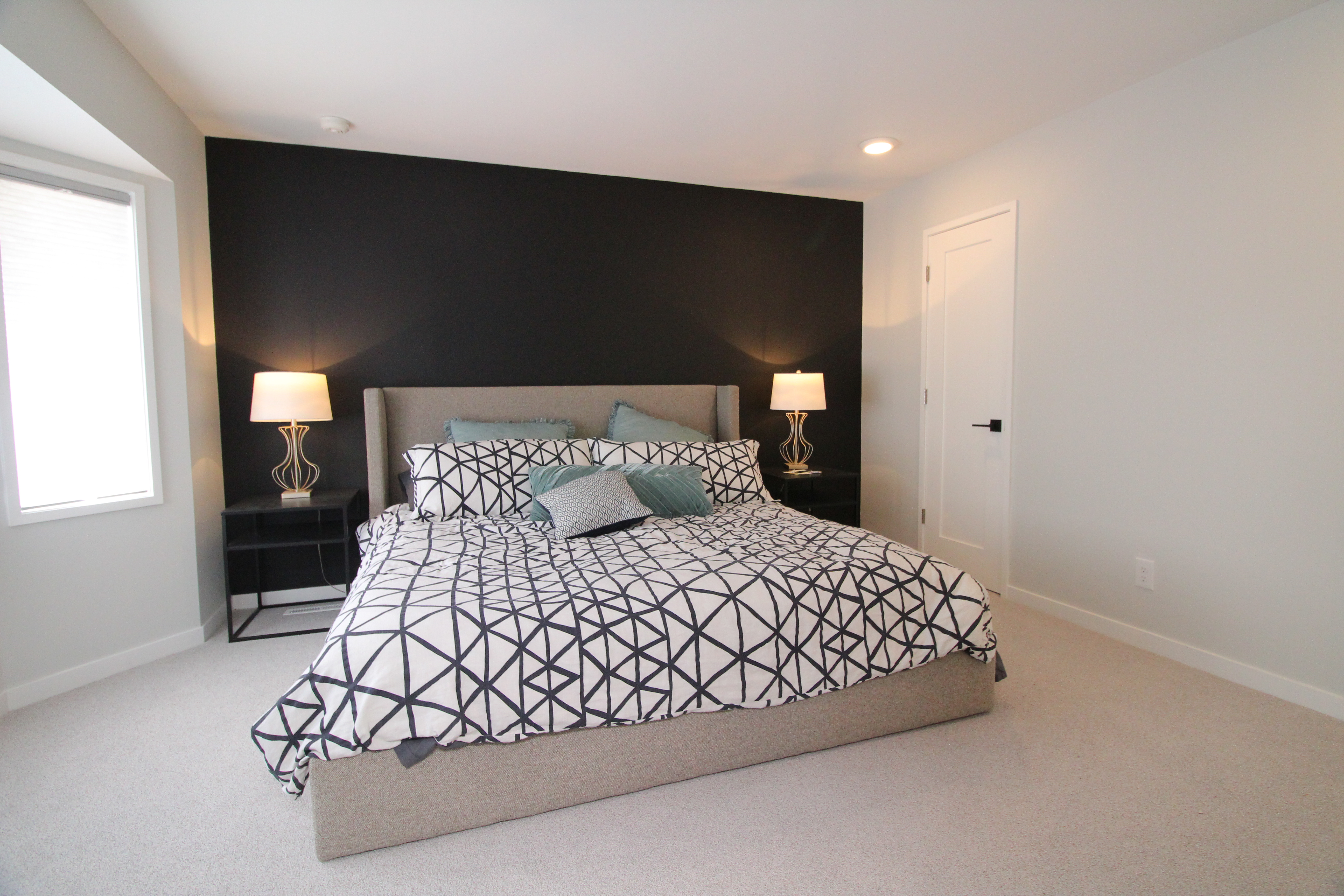 Primary bedroom with dark accent wall, upholstered bed, and modern bedside lighting.