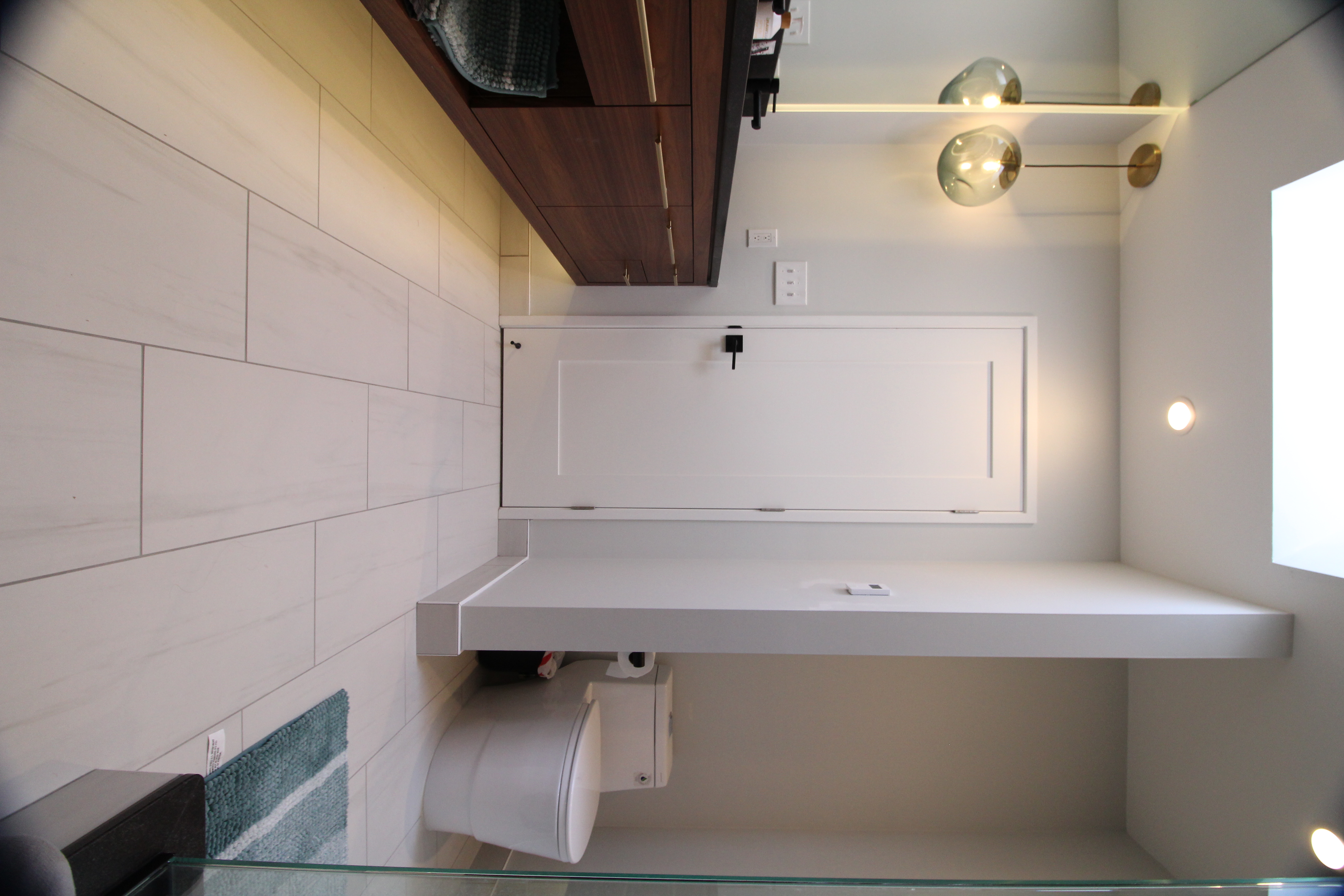 Bathroom view showing walnut vanity, large-format floor tile, and clean-lined modern fixtures.
