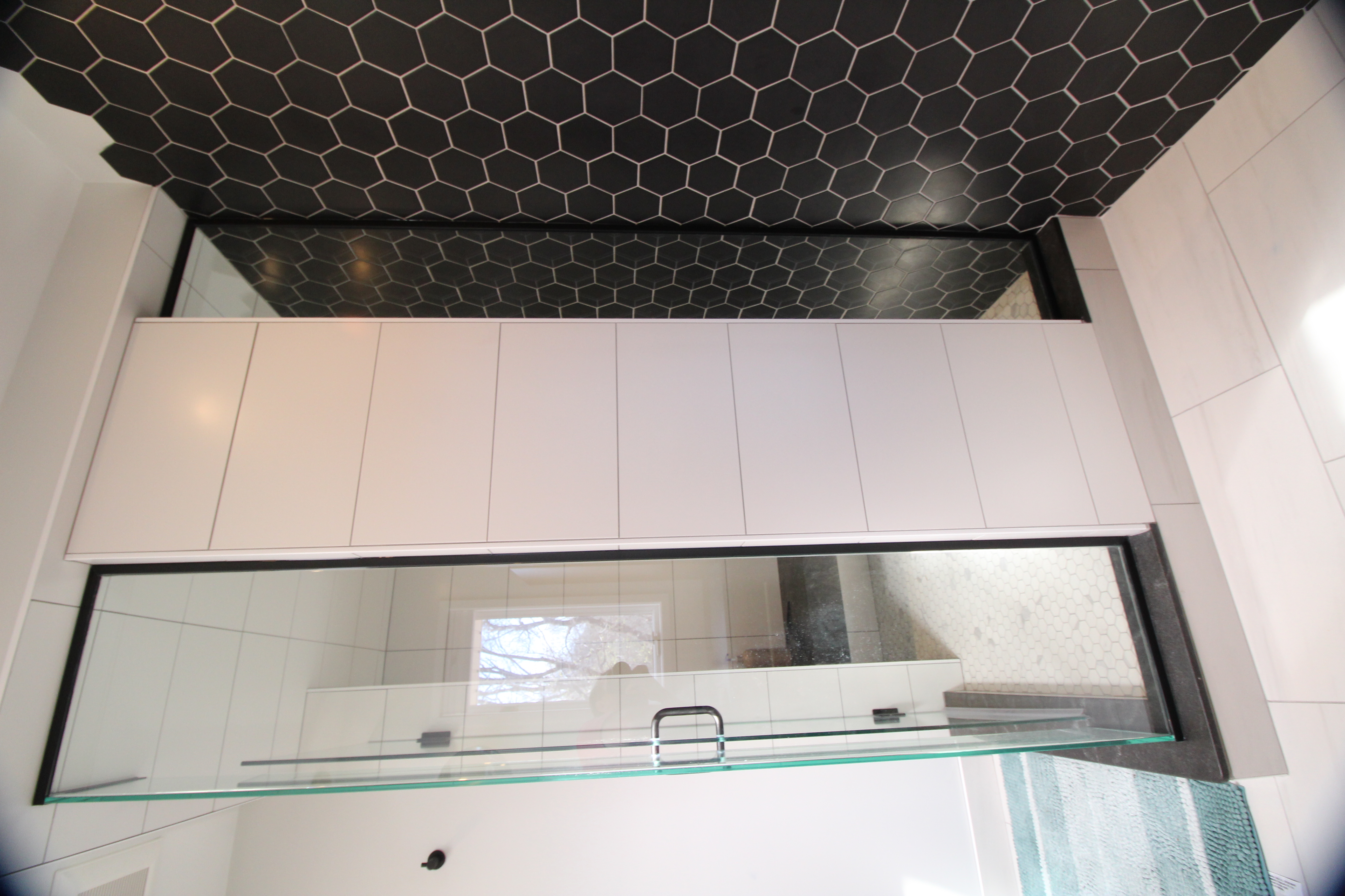 Frameless shower glass with black accent tile wall and bright, modern bathroom finishes.
