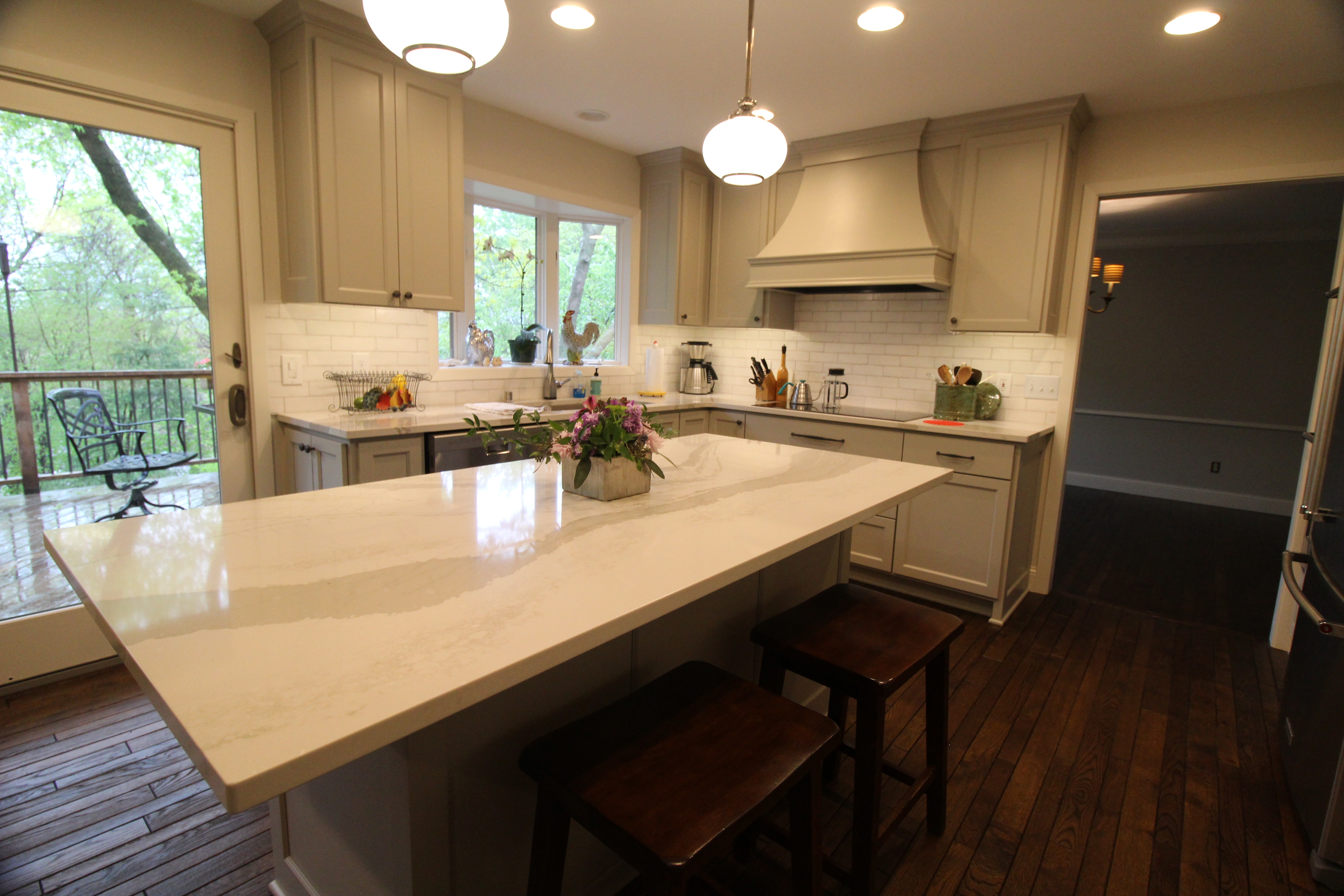 Range wall detail with statement hood, classic white subway tile, and a sleek cooktop set into quartz countertops.