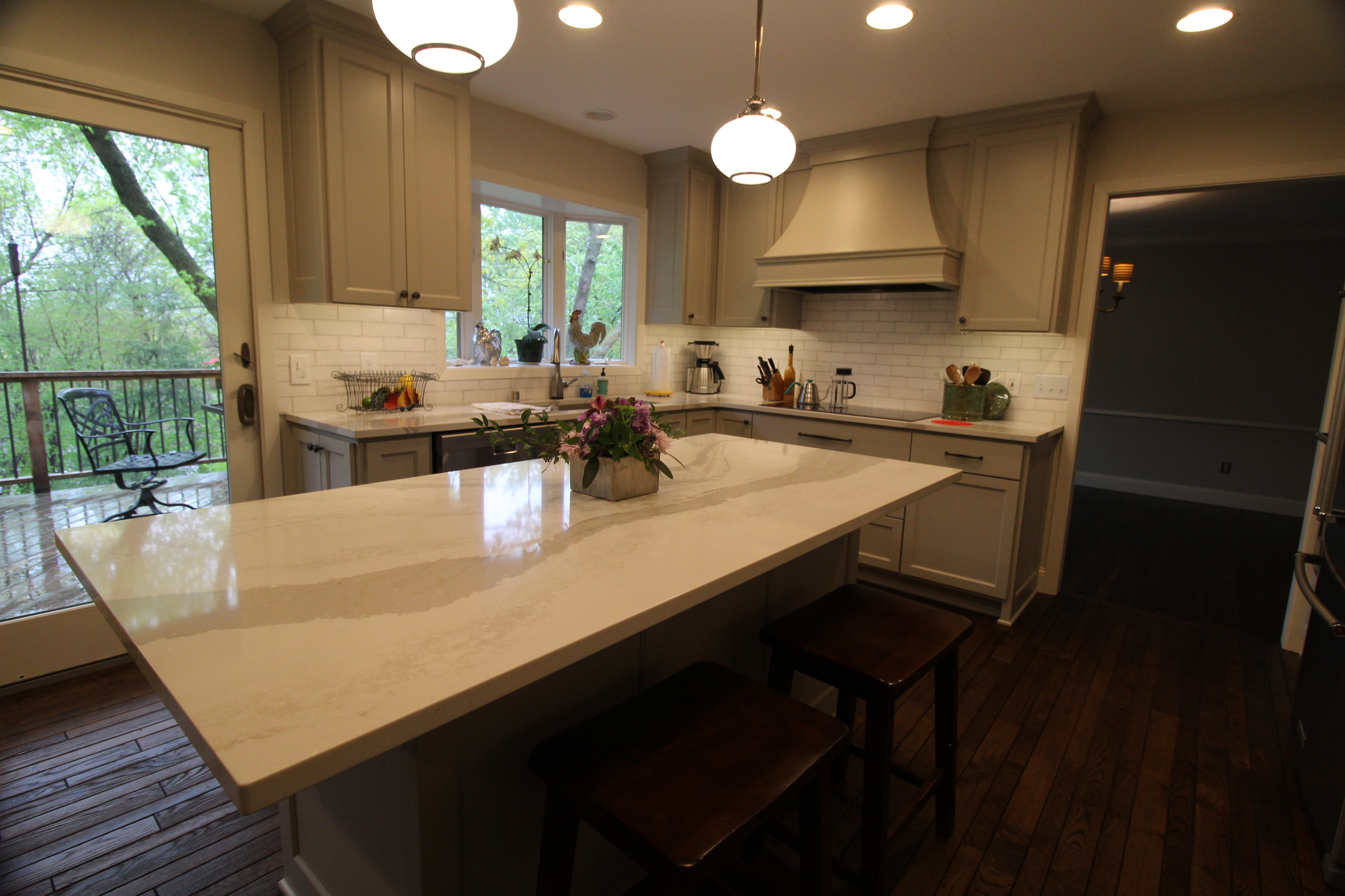 Open kitchen view with glass-front cabinets, stainless appliances, and expansive quartz surfaces for a bright, modern classic look.