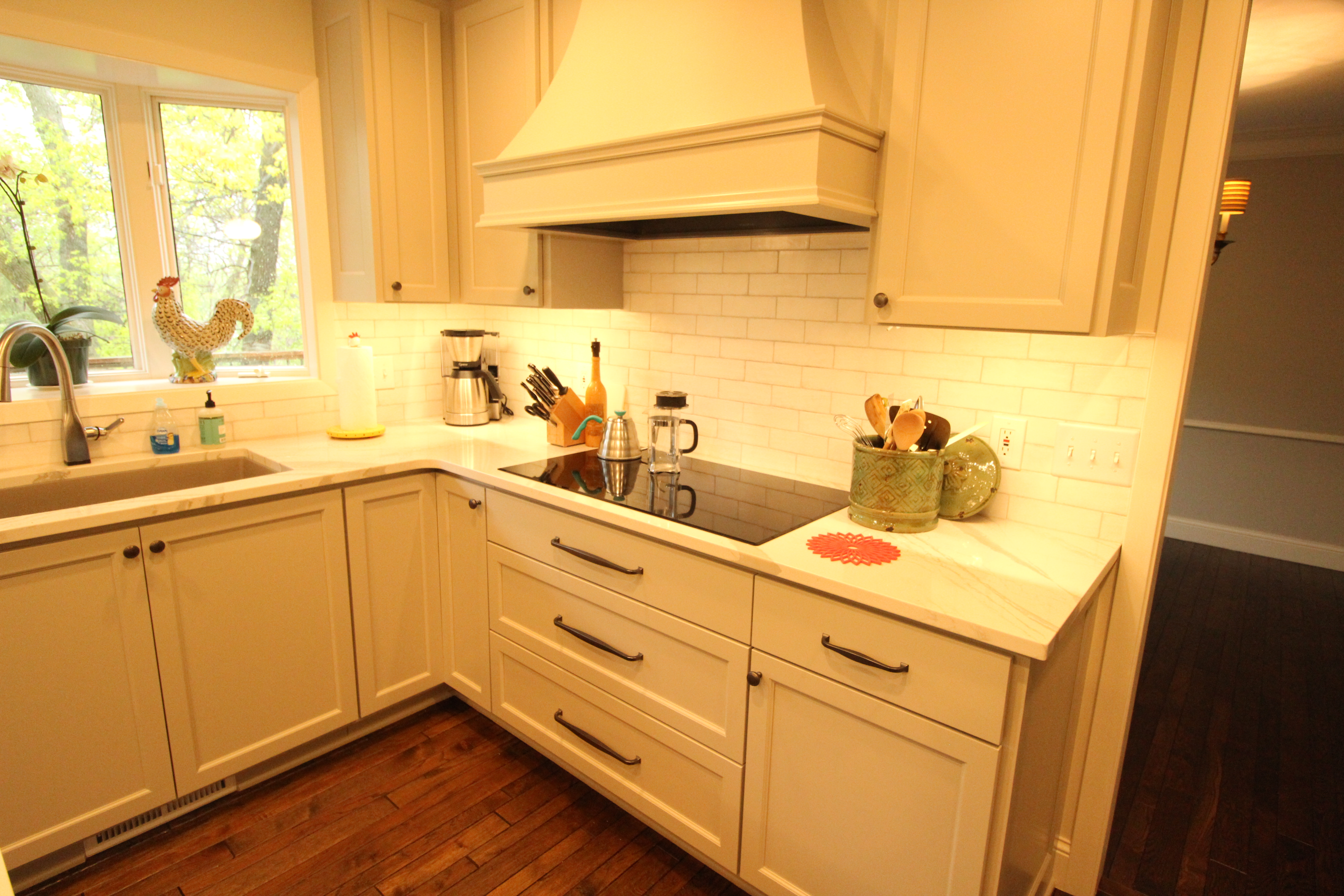Warm, inviting view of the kitchen island and range wall, emphasizing lighting, finishes, and open flow.